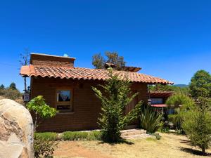 una pequeña casa con techo de baldosas rojas en Cabaña Puma Tapalpa, en Tapalpa