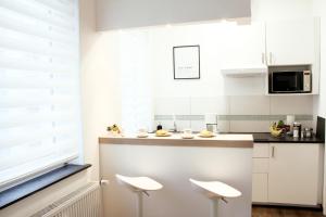 a kitchen with white cabinets and white stools at SECRET HIDEAWAYS cozySTUDIO 2 superior Apartment mit WiFi nahe Uni l Messe l Flughafen l Zoo in Duisburg