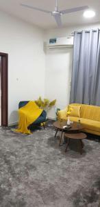 a living room with a yellow couch and a table at شقة السلمة أم القيوين in Umm Al Quwain