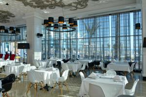 a restaurant with white tables and chairs and large windows at Vikingen Infinity Resort & Spa in Avsallar