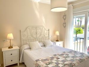 a bedroom with a bed with a white bedspread and a window at Casa El Faro in El Rompido
