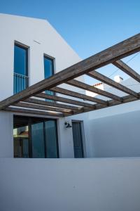 a wooden pergola on the side of a white building at Vida na Vila in Vila Nova de Milfontes