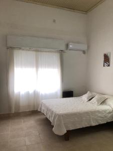 a bedroom with a white bed and a window at Acogedor departamento bien ubicado in Concordia