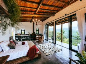 a bedroom with a bed and a living room with windows at Pousada Viver a Pedra in Gonçalves