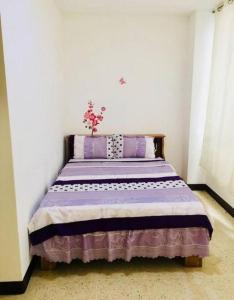 a bedroom with a bed with purple and white sheets at La Fortuna Roja in San José