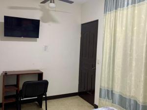 a room with a black door and a desk and a ceiling fan at La Fortuna Roja in San José