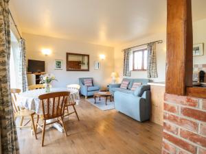 a living room with a blue couch and a table at Barn Owl Cottage in Little Glenham +8 photos