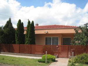 a house with a red fence and trees at Bokréta Üdülő in Mezőkövesd