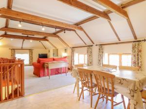 a living room with a table and chairs and a piano at Hayloft Cottage in Little Glenham