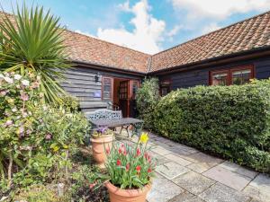 uma casa com um jardim com um banco e flores em Poppy Cottage em Little Glenham