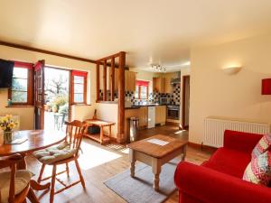 a living room with a red couch and a table at Poppy Cottage in Little Glenham