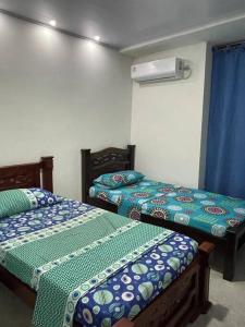 2 camas en una habitación con sábanas azules y verdes en Casa Vacacional Villanueva en Villanueva