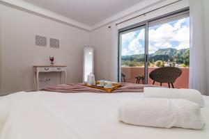a white bedroom with a bed and a large window at Furnas Apartment in Furnas