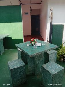 una mesa verde y bancos con un jarrón de flores. en 'Franklyn', Homestay en Kalutara
