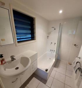 uma casa de banho branca com um lavatório e um chuveiro em Magnetic Diamond - Gorgeous Holiday Chalet em Nelly Bay