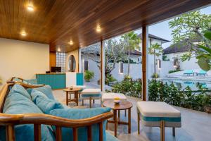 an outdoor living room with a blue couch and tables at Ecozy Dijiwa Canggu in Canggu