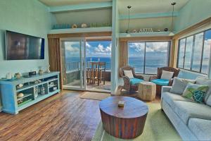 a living room with a couch and a tv and a table at Sealodge G9 in Princeville