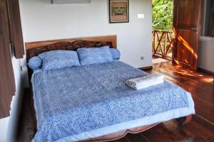 um quarto com uma cama com um cobertor azul e almofadas em Boa Hill Surf House em Nembrala