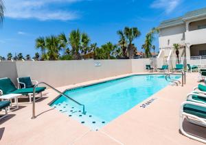 a swimming pool with chaises and chairs next to a building at Moon Dancer Condominiums in South Padre Island