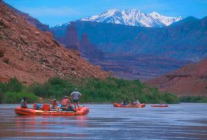 a group of people rafting down a river in canoes at Big Horn Lodge in Moab