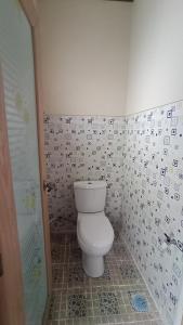 La salle de bains est pourvue de toilettes et d'un mur carrelé. dans l'établissement DIENG GHUZY HOUSE syariah family room, à Wonosobo