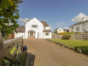 a white house with a fence and a brick driveway at The Meadows in Pentraeth