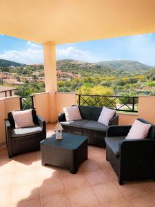 a balcony with couches and chairs and a view of a mountain at Casa Carmen - Attico vista mare in Porto San Paolo