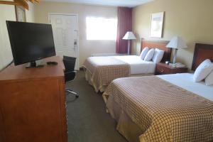 a hotel room with two beds and a flat screen tv at Sunset Inn - Augusta in Augusta