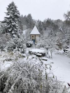 a snow covered garden with a small house in the background at LES ANDALOUSES in Avèze