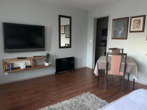 a living room with a table and a flat screen tv at Opanuku Out West in Auckland