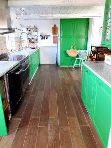 a kitchen with green cabinets and a wooden floor at Beachhouse Langeland in Tranekær