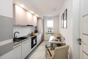 a kitchen with white cabinets and a small table at Pokoje Wita Stwosza in Warsaw