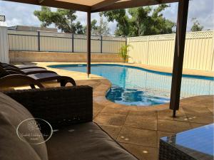 a swimming pool with chairs and an umbrella at Seashells Holiday House - Kalbarri in Kalbarri