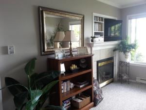 een woonkamer met een open haard en een spiegel bij Hammond Bay Oceanside Guesthouse in Nanaimo