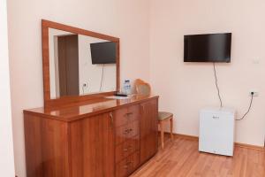 een kamer met een dressoir met een spiegel en een televisie bij GYM Inn in Tasjkent