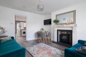 sala de estar con sofá azul y chimenea en April Cottage, en Paignton