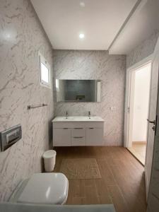 a white bathroom with a sink and a mirror at Magnifique Villa moderne piscine SANS VIS À VIS DJERBA Midoun in Taguermess