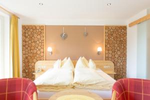 a bedroom with a bed with white pillows at Hotel Garni Grünmoos in Sankt Jakob in Defereggen