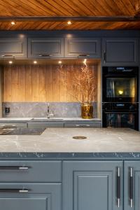 a kitchen with blue cabinets and a counter top at Skeikampen cabin with mountain view, jacuzzi, and 8 bedrooms in Aulstad