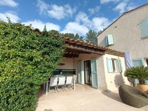 a patio of a house with chairs and a hedge at Villa la Grette in Fayence