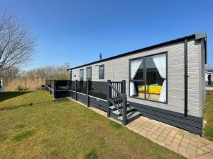 a gray house with a large window on a field at Indulgence Lakeside Lodge i3 with hot tub, private fishing peg situated at Tattershall Lakes Country Park in Tattershall