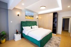 a bedroom with a large bed with a green headboard at COZY 3-BEDROOM SERVICED APARTMENT IN LAVINGTON BY COZY HOMEs in Nairobi