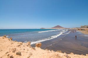 a beach with people in the water and a group of people at Alquilaencanarias- Medano Amanecer Cabezo Beach in El Médano