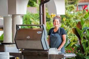 a woman standing in front of a grill at Hotel-Restaurant Sonnhof in Radfeld