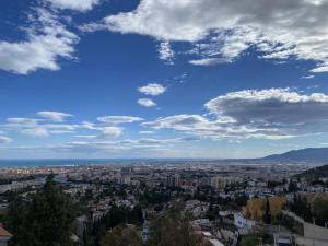 una vista di una città sotto un cielo azzurro con nuvole di Bed & Breakfast Villa Botánica a Málaga