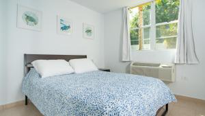 a white bedroom with a bed and a window at Landing View 304 with rooftop terrace in Rincon +20 photos