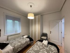 a bedroom with two beds and a chair in it at LORE - Parking y bicis gratis in San Sebastián