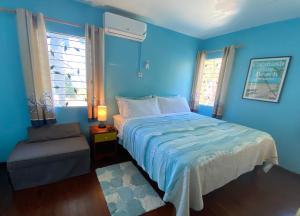 a blue bedroom with a bed and a chair at The Blue Orchid B&B in Montego Bay