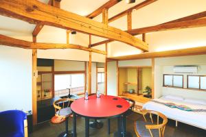 藤沢市にあるオーシャンビュー 加美屋リゾート 江ノ島,江ノ島の島内,仲見世通りから3分,海と日の出を臨む貸切の和モダン別荘の赤いテーブルと椅子、ベッドが備わる客室です。