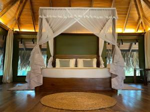 a bed with a canopy in a room with a rug at Yala Lake View Cabanas in Tissamaharama